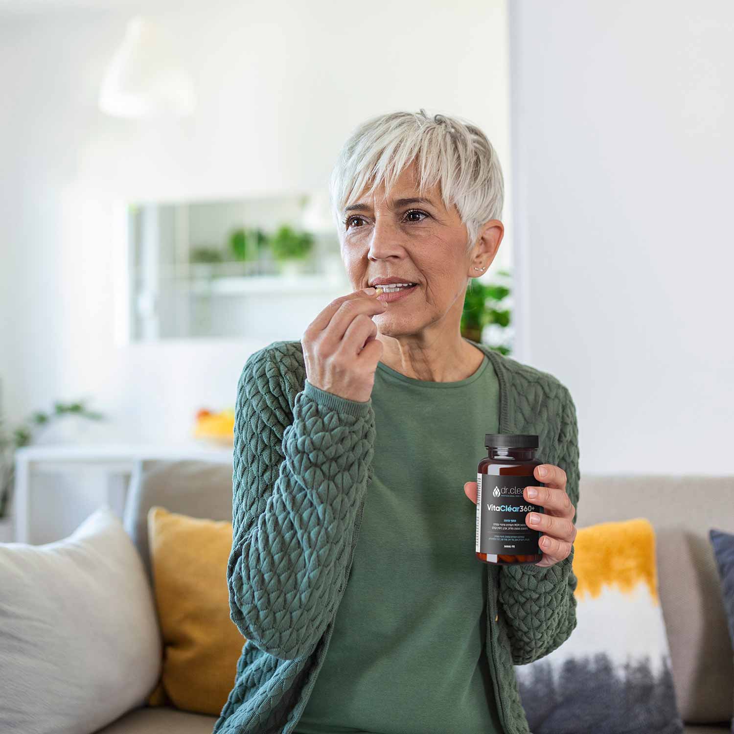 אישה מבוגרת אוחזת ביד את הבקבוק הממותג של תוסף התזונה לחיזוק הציפורן ויטה קליר 360 פלוס